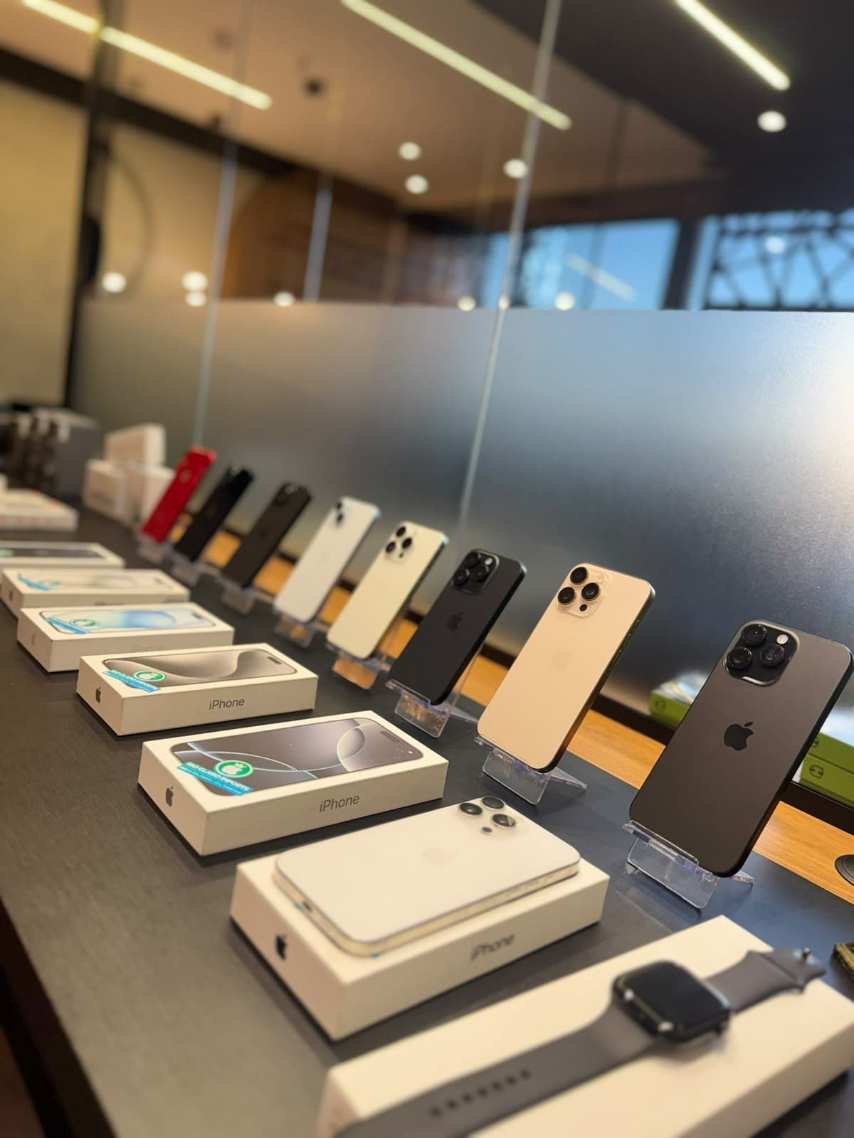 Vitrine da loja com iPhones expostos em suportes e caixas lacradas no balcão